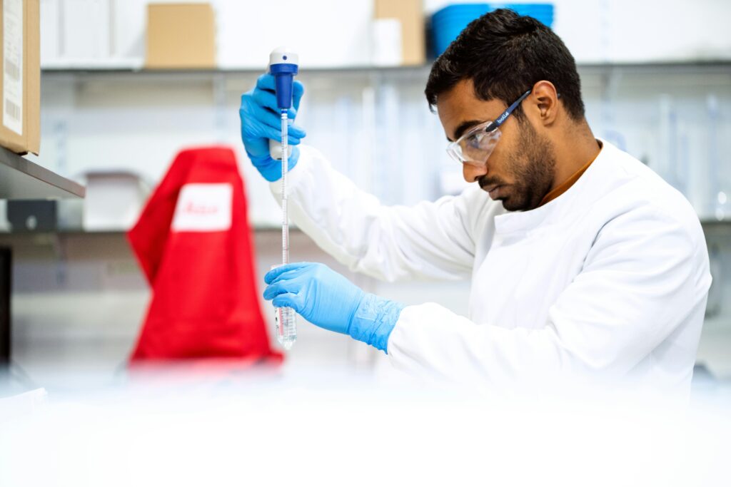 A focused scientist holding a pipette in a laboratory environment.